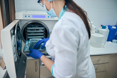Dentista realizando a inclusão dos instrumentais dentro da autoclave para fazer a esterilização dos materiais