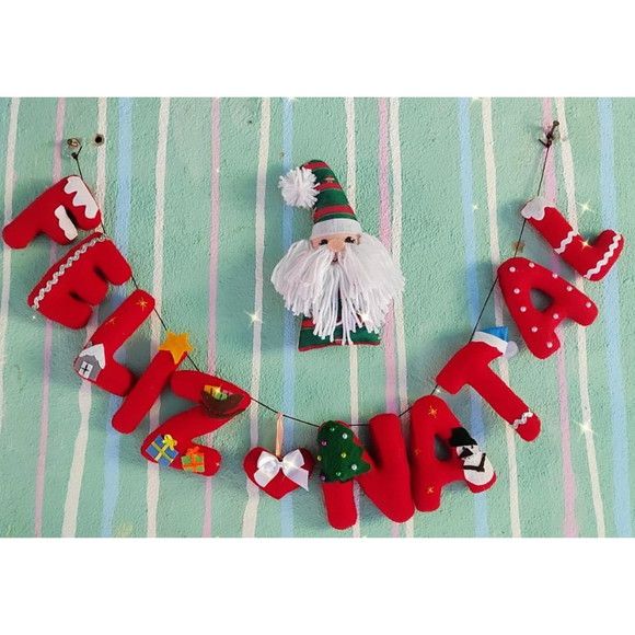 Varal escrito feliz natal pendurado em uma parede verde agua claro com um pequeno boneco do papai noel junto