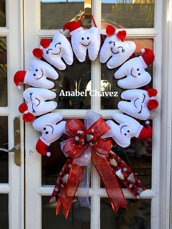 Guirlanda de Natal feita com dentes de pel&uacute;cia brancos e detalhes em vermelho, com la&ccedil;o decorativo.