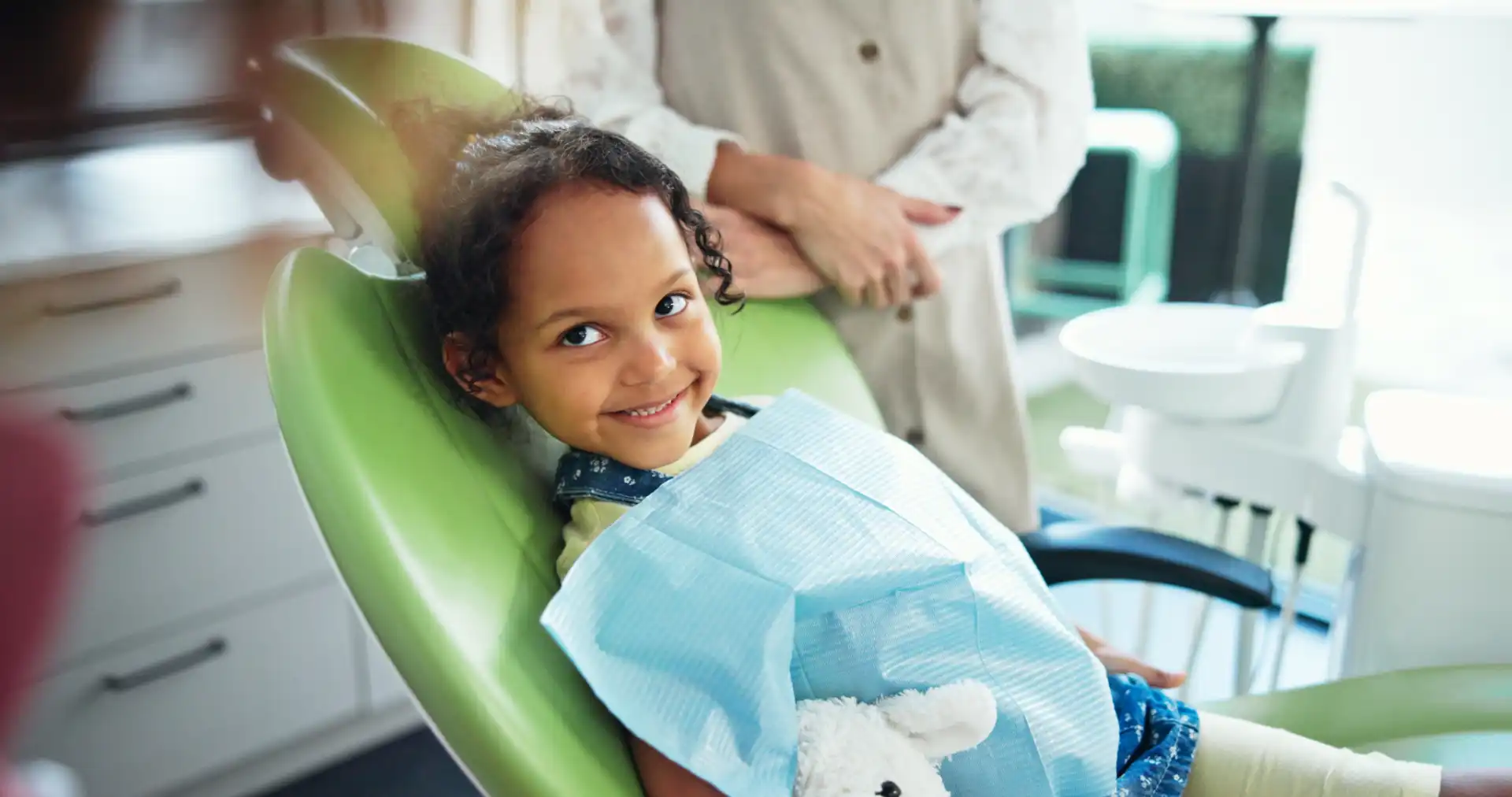 Menina sorridente na cadeira do dentista após o escaneamento intraoral na odontopediatria.