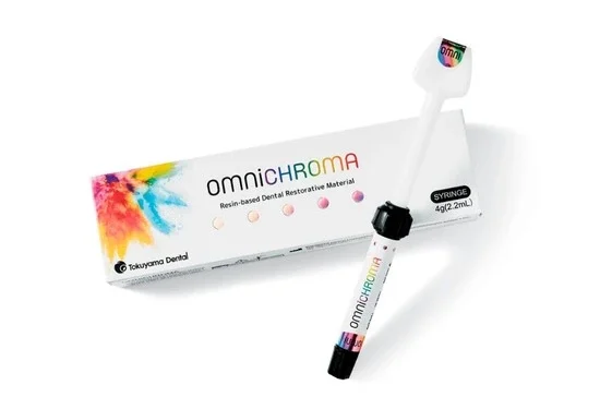 Imagem de um kit de resina odontológica Omnichroma com tubo de resina, pistola de aplicação e embalagem colorida, ideal para restaurações dentárias.